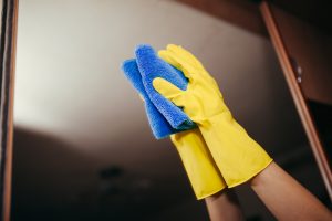 Hand in rubber glove wiping a mirror with a cloth