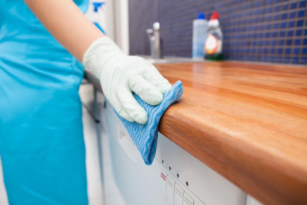a uniformed cleaner wiping down a kitchen surface